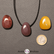 Drei rote und gelbe Mookait gebohrte Trommelsteine nebeneinander. Einer befindet sich an einem schwarzen gewachsten Baumwollband.