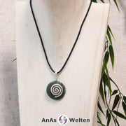 Ein Moosachat Donut an einem Donut-Halter Spirale, der mit einem gewachsten Baumwollband um eine helle Büste hängt.