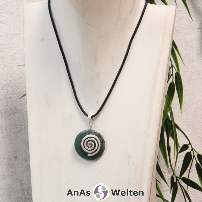 Ein Moosachat Donut an einem Donut-Halter Spirale, der mit einem gewachsten Baumwollband um eine helle Büste hängt.