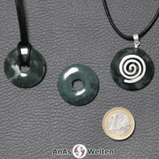 Drei Moosachat Donuts nebeneinander. Einer an einem Baumwollband, ein anderer an einem Donut-Halter mit Baumwollband.