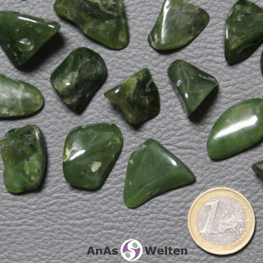 Das Bild zeigte einen Nephrit Jade Trommelstein anhand mehrerer Beispielsteine. Die Farbe der Edelsteine ist eine Mischung aus dunklen und hellen Grüntönen. Außerdem gibt es gelegentliche weiße Einschlüsse.