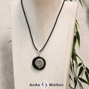 Ein Onyx Donut an einem Donut-Halter Spirale, der mit einem gewachsten Baumwollband um eine helle Büste hängt.