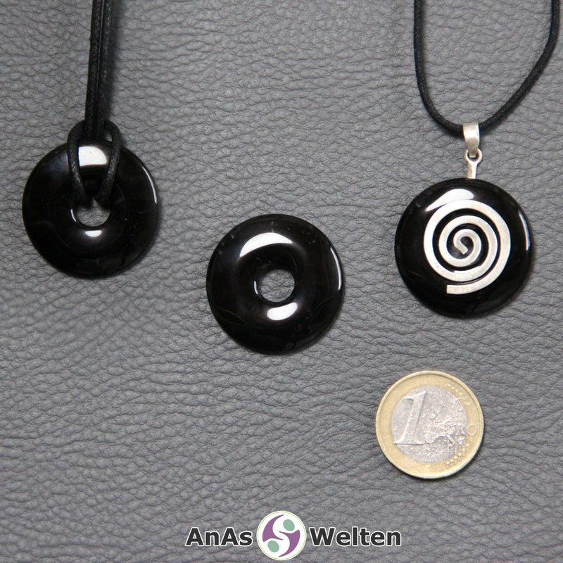 Drei Onyx Donuts nebeneinander. Einer an einem Baumwollband, ein anderer an einem Donut-Halter mit Baumwollband.