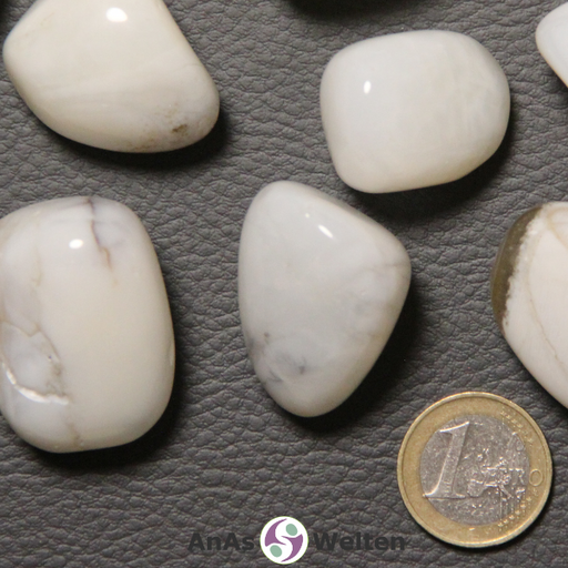 Das Bild zeigt einen Opal (weiß) Trommelstein anhand mehrerer Beispielbilder. Die Steine sind vergleichsweise groß und haben eine hauptsächlich weiße Farbe. Außerdem haben sie gelegentlich braune oder schwarze Einschlüsse.