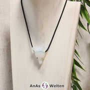 Ein Opalglas Wolf Anhänger an einem schwarzen Baumwollband, der um eine helle Büste gehängt wurde.