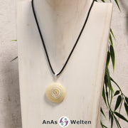 Ein Orangencalcit Donut an einem Donut-Halter Spirale, der mit einem gewachsten Baumwollband um eine helle Büste hängt.