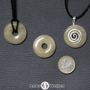 Drei Orangencalcit Donuts nebeneinander. Einer an einem Baumwollband, ein anderer an einem Donut-Halter mit Baumwollband.