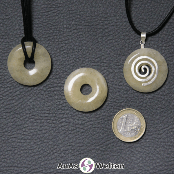 Drei Orangencalcit Donuts nebeneinander. Einer an einem Baumwollband, ein anderer an einem Donut-Halter mit Baumwollband.