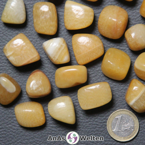 Das Bild zeigt einen Orangencalcit Trommelstein anhand mehrerer Beispielsteine. Die Edelsteine haben eine gelbe bis orangene Farbe. Außerdem haben viele von ihnen weiße bis hellgelbe Einschlüsse.