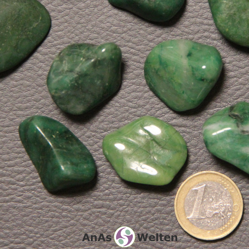 Das Bild zeigt einen Prasem Trommelstein anhand mehrerer Beispielsteine. Die Edelsteine haben alle eine grüne Farbe. Einige sind hellgrün, andere dunkelgrün und andere beides. Außerdem haben sie gelegentliche braune, graue und schwarze Einschlüsse.