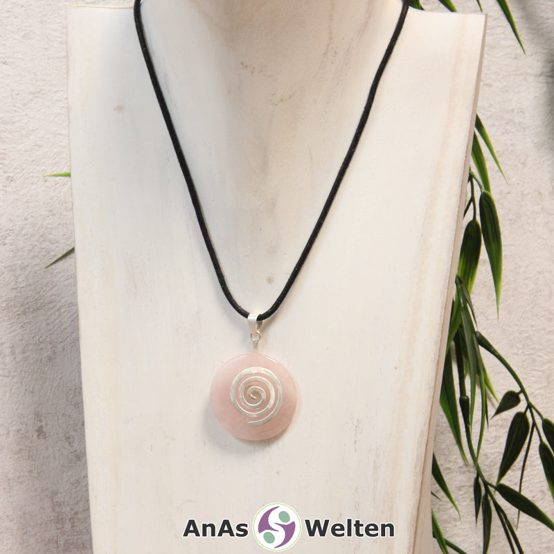 Ein Rosenquarz Donut an einem Donut-Halter Spirale, der mit einem gewachsten Baumwollband um eine helle Büste hängt.