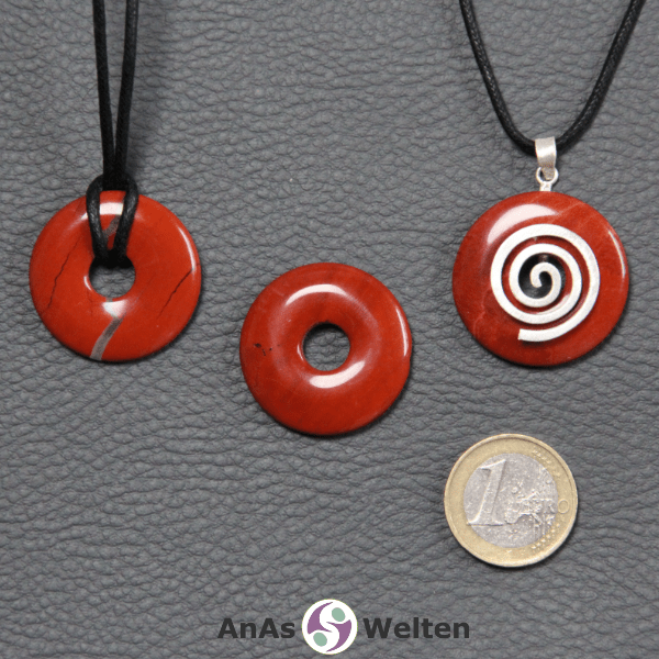 Drei Roter Jaspis Donuts nebeneinander. Einer an einem Baumwollband, ein anderer an einem Donut-Halter mit Baumwollband.