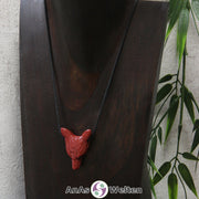 Ein Roter Jaspis Wolf Anhänger an einem schwarzen Baumwollband, der um eine dunkle Büste gehängt wurde.