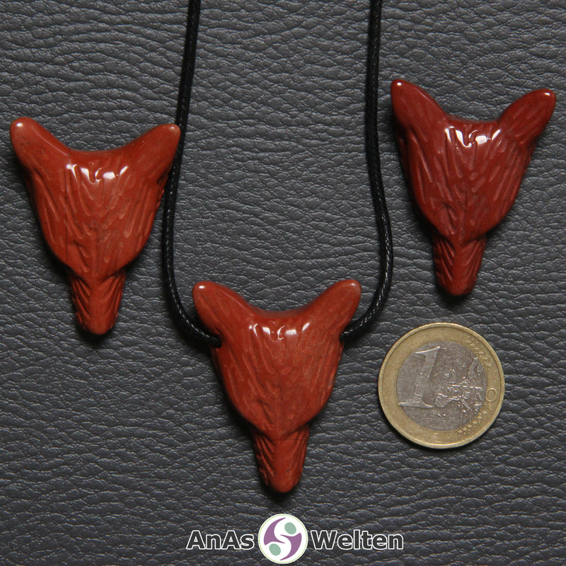 Drei Roter Jaspis Wolf Anhänger nebeneinander. Einer befindet sich an einem schwarzen Baumwollband.