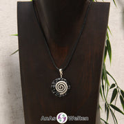 Ein Schneeflocken-Obsidian Donut an einem Donut-Halter Spirale, der mit einem gewachsten Baumwollband um eine dunkle Büste hängt.