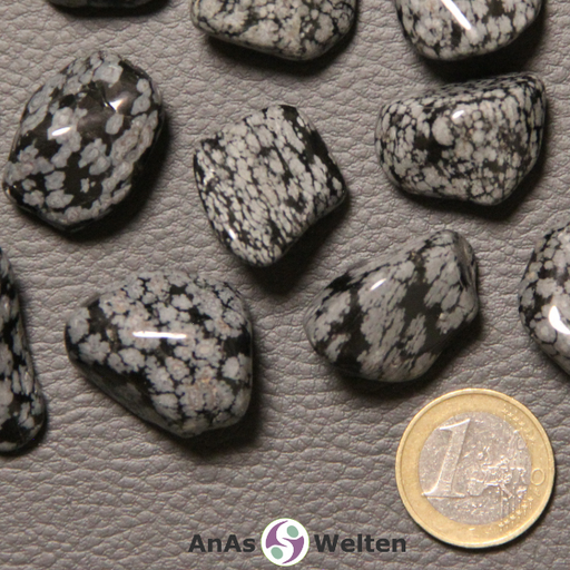 Das Bild zeigt einen Schneeflocken-Obsidian Trommelstein anhand mehrerer Beispielbilder. Die Edelsteine haben allesamt eine schwarze Grundfarbe mit vielen kleineren und größeren grau-weißen Einschlüssen.