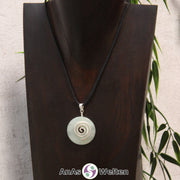 Ein Serpentin Donut an einem Donut-Halter Spirale, der mit einem gewachsten Baumwollband um eine dunkle Büste hängt.