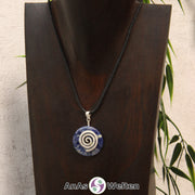 Ein Sodalith Donut an einem Donut-Halter Spirale, der mit einem gewachsten Baumwollband um eine dunkle Büste hängt.