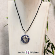 Ein Sodalith Donut an einem Donut-Halter Spirale, der mit einem gewachsten Baumwollband um eine helle Büste hängt.