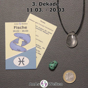 Die Sternzeichenkarte und je ein beispielhafter gebohrter Girasolquarz Trommelstein am Band und ein Türkis Trommelstein der 3. Dekade liegen nebeneinander.