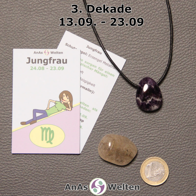 Die Sternzeichenkarte und je ein beispielhafter gebohrter Amethyst Trommelstein am Band und ein Rutilquarz Trommelstein der 3. Dekade liegen nebeneinander.