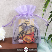 Ein beispielhaftes Sternzeichen Steine Set Löwe mit Karte, Trommelstein und Edelsteinkette in einem lila Organzabeutel.