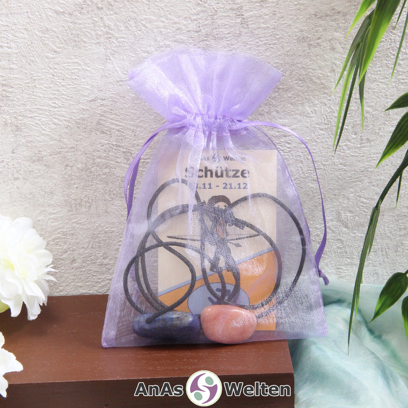 Ein beispielhaftes Sternzeichen Steine Set Schütze mit Karte, Trommelstein und Edelsteinkette in einem lila Organzabeutel.