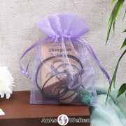 Ein beispielhaftes Sternzeichen Steine Set Skorpion mit Karte, Trommelstein und Edelsteinkette in einem lila Organzabeutel.