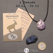 Die Sternzeichenkarte und je ein beispielhafter gebohrter Amethyst Trommelstein am Band und ein Dumortierit Trommelstein der 1. Dekade liegen nebeneinander.