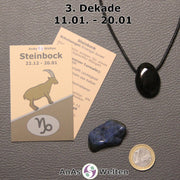 Die Sternzeichenkarte und je ein beispielhafter gebohrter Onyx Trommelstein am Band und ein Dumortierit Trommelstein der 3. Dekade liegen nebeneinander.