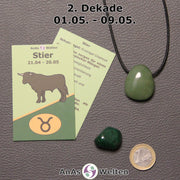 Die Sternzeichenkarte und je ein beispielhafter gebohrter Aventurin Trommelstein am Band und ein Malachit Trommelstein der 2. Dekade liegen nebeneinander.