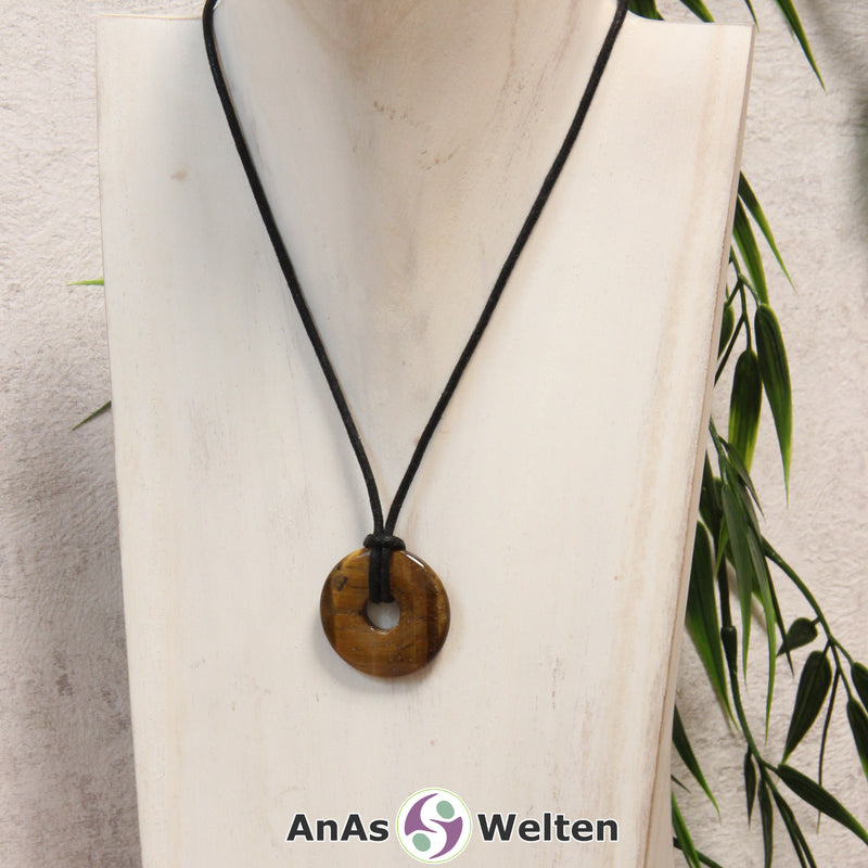 Ein Tigerauge Donut als Kette an einem schwarzen gewachsten Baumwollband um eine weiße Büste.