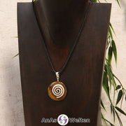 Ein Tigerauge Donut an einem Donut-Halter Spirale, der mit einem gewachsten Baumwollband um eine dunkle Büste hängt.