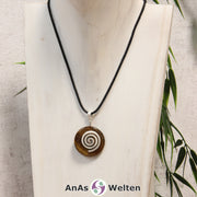 Ein Tigerauge Donut an einem Donut-Halter Spirale, der mit einem gewachsten Baumwollband um eine helle Büste hängt.