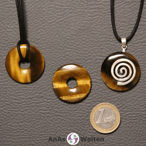 Drei Tigerauge Donuts nebeneinander. Einer an einem Baumwollband, ein anderer an einem Donut-Halter mit Baumwollband.