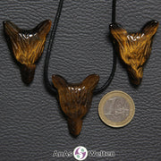 Drei Tigerauge Wolf Anhänger nebeneinander. Einer befindet sich an einem schwarzen Baumwollband.