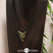 Ein Unakit Wolf Anhänger an einem schwarzen Baumwollband, der um eine dunkle Büste gehängt wurde.