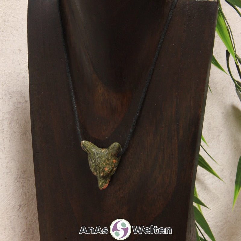 Ein Unakit Wolf Anhänger an einem schwarzen Baumwollband, der um eine dunkle Büste gehängt wurde.